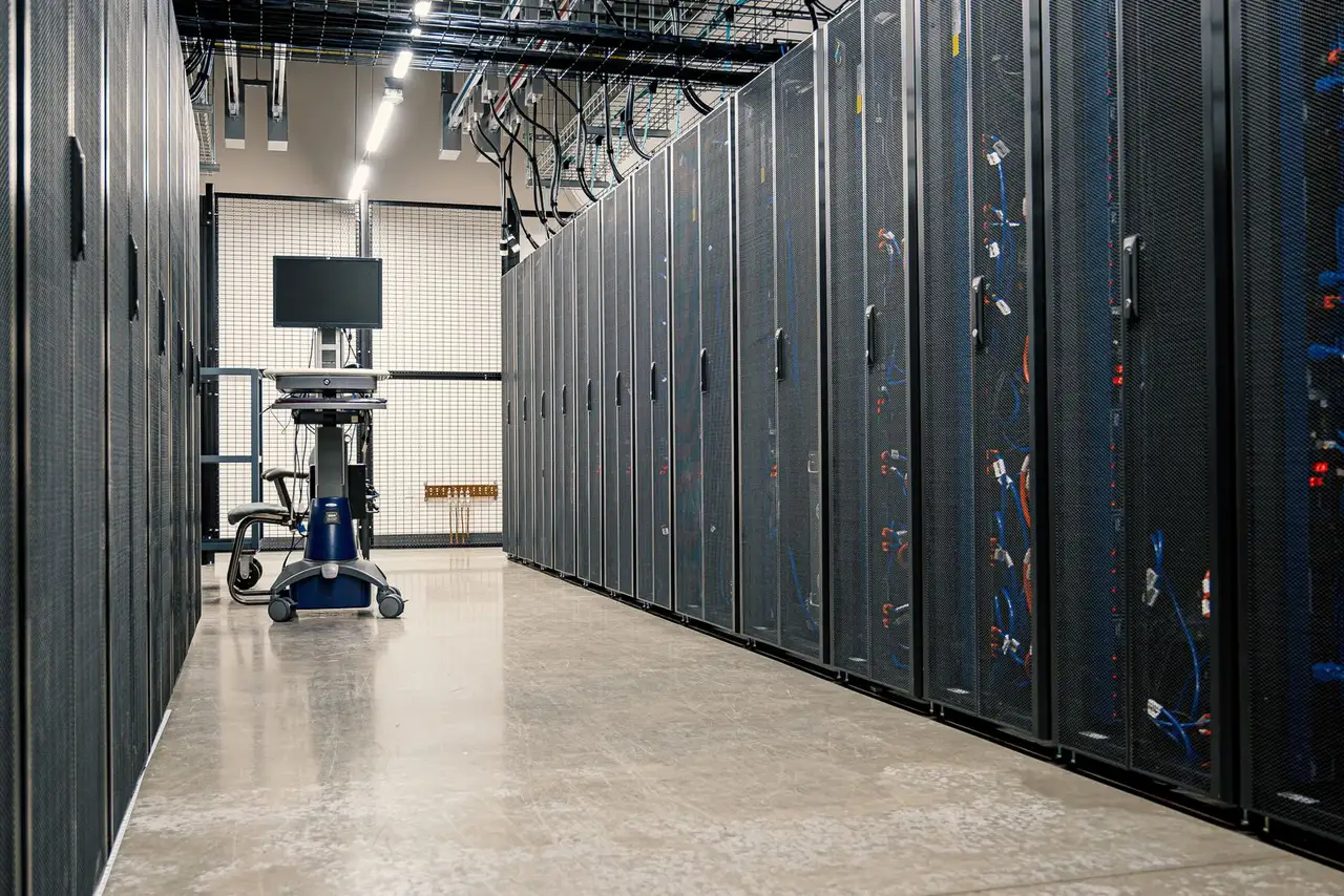 Data center aisle with server racks, overhead cable tray, and a mobile workstation cart